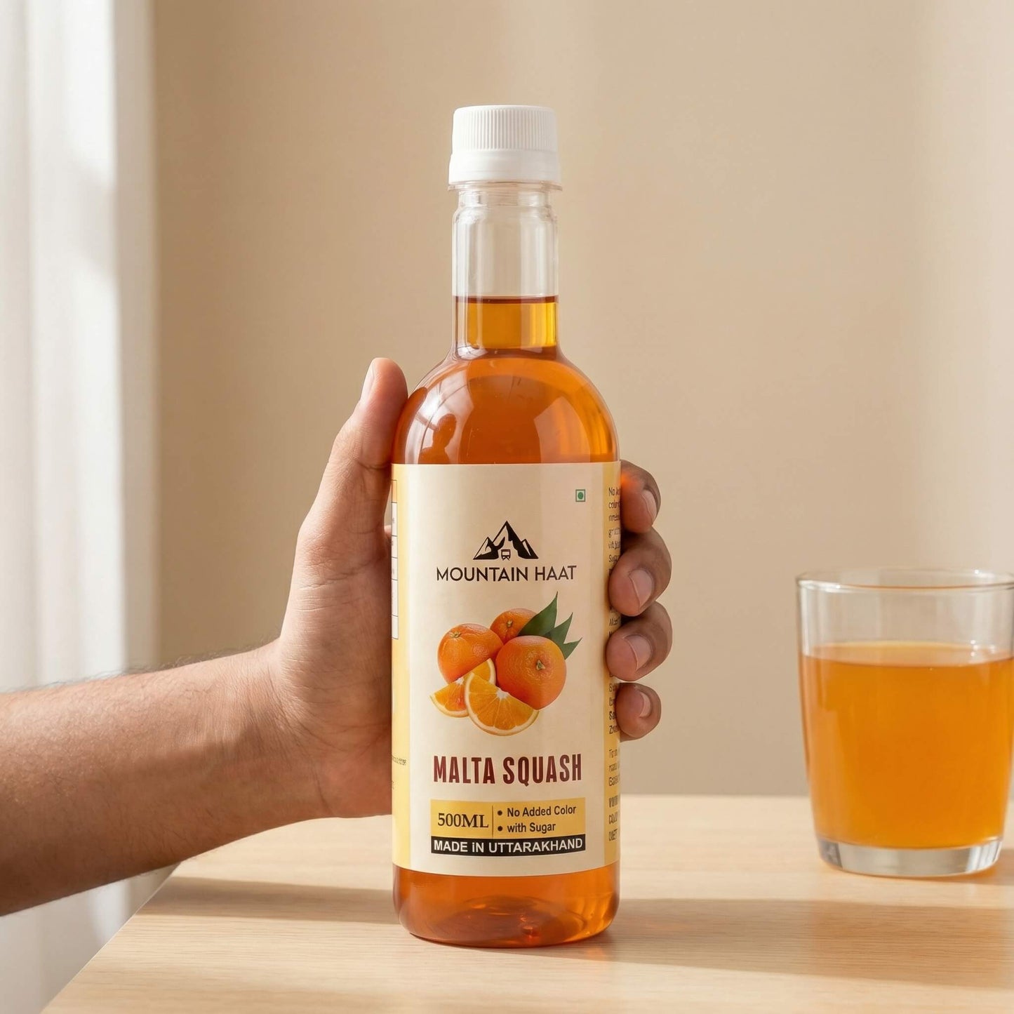 Mountain Haat Malta Squash 500ml classic sweetened version with sugar, held in hand, made in Uttarakhand.